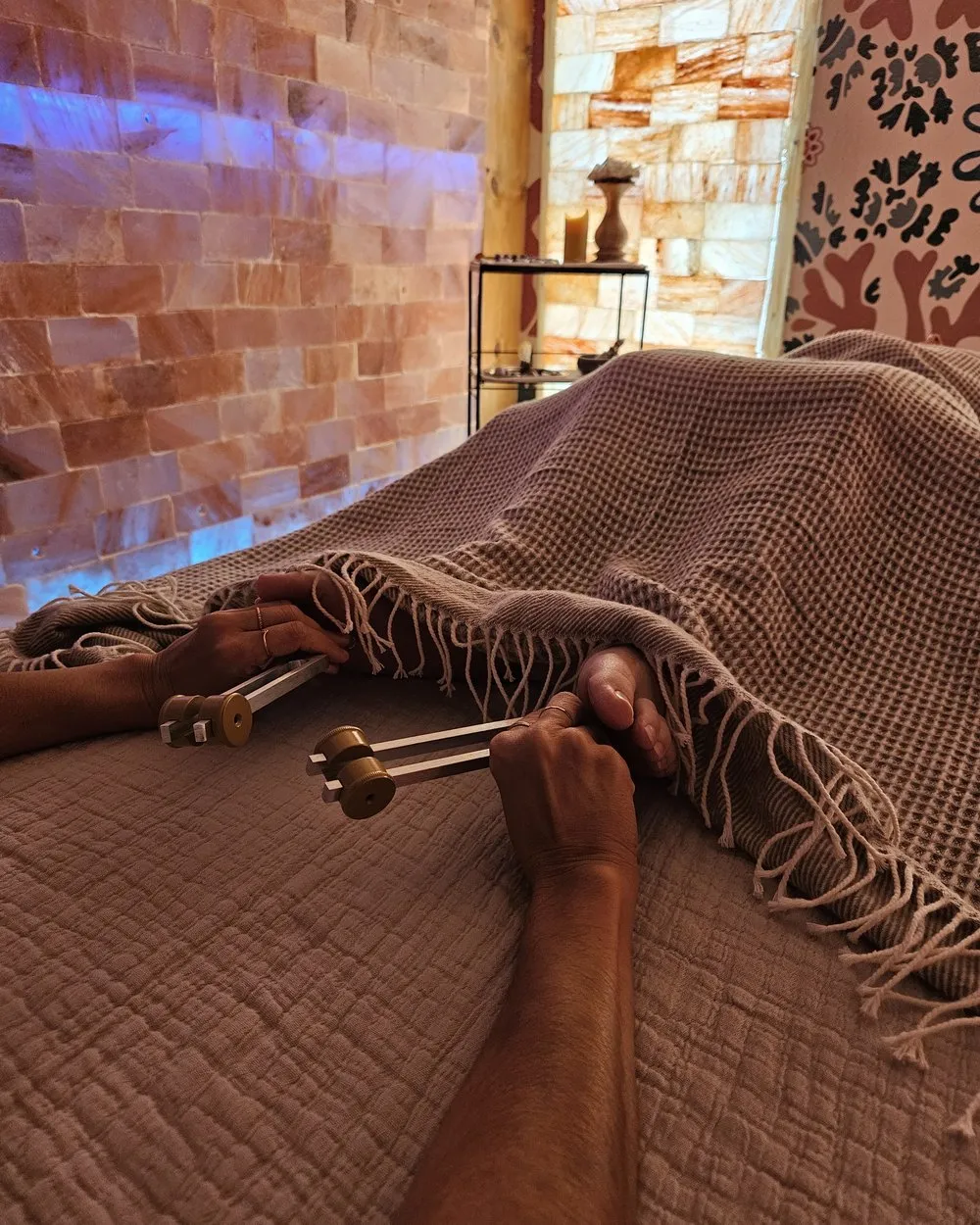 Hands holding tuning forks on a session bed